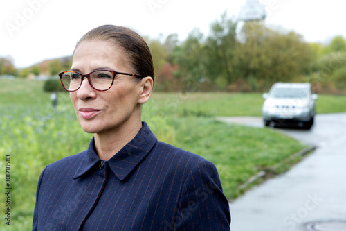 Smiling businesswoman with eyeglasses next to field