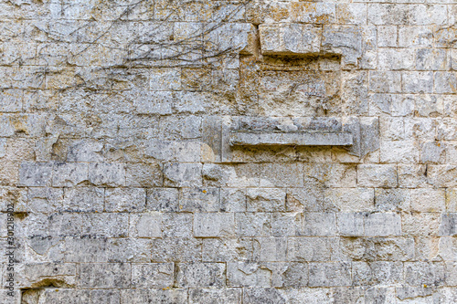 old grey rectangular stone wall with many rough edges and old closed windows