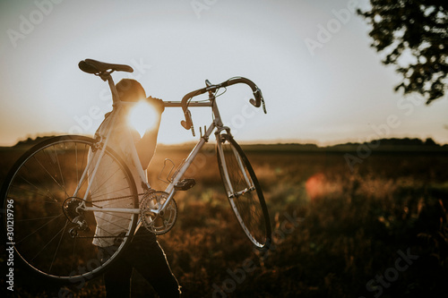 Man carrying a racing cycle in thesun
