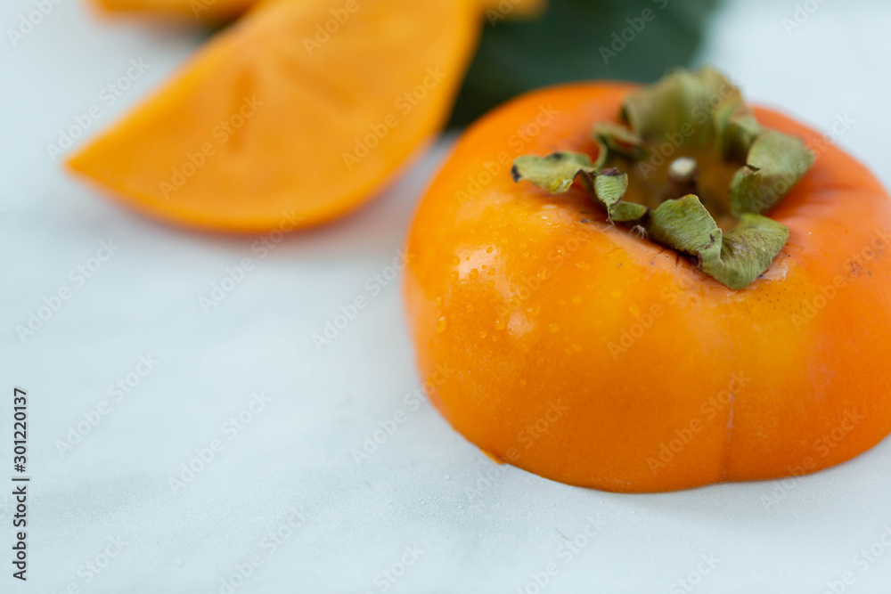 Macro of sliced persimmon fruit on marble background