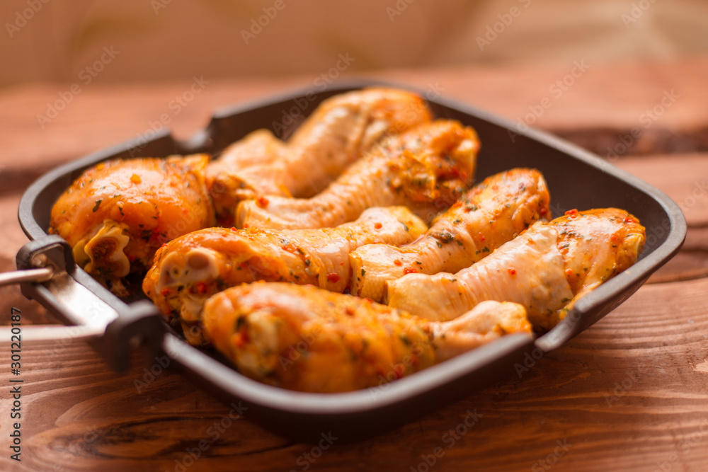 Raw chicken drumsticks in sauce and spices in a pan not a wooden background. Raw chicken drumsticks in sauce and spices in a pan not a wooden background.