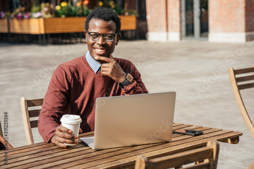 Young man using laptop in a coffee shop, drinking coffee photo