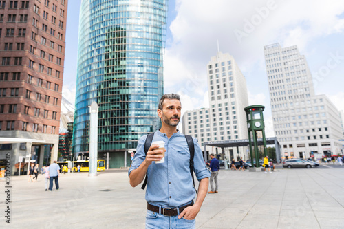 Man in the city holding a cup of coffee, Berlin, Germany