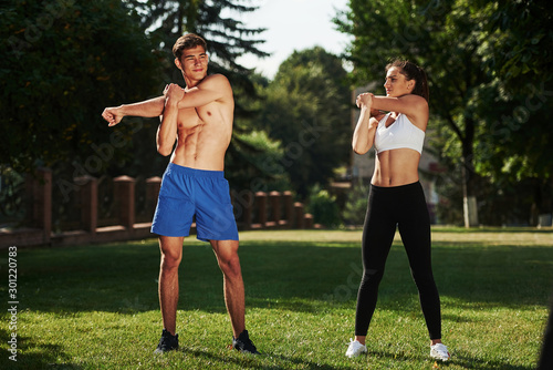 Warm up exercises. Man and woman have fitness day in the city at daytime in the park © standret