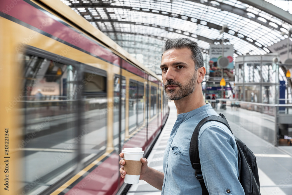 Man with takeaway coffee at the station while train coming in, Berlin, Germany Man with takeaway coffee at the station while train coming in, Berlin, Germany
