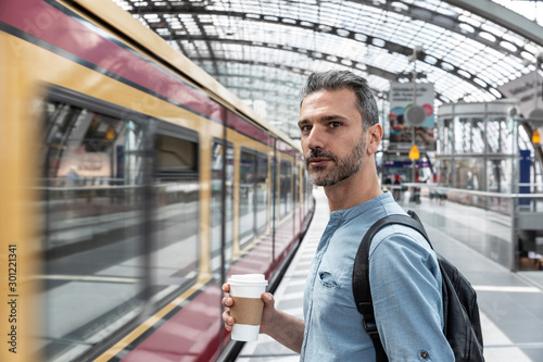 Wallpaper Mural Man with takeaway coffee at the station while train coming in, Berlin, Germany Torontodigital.ca