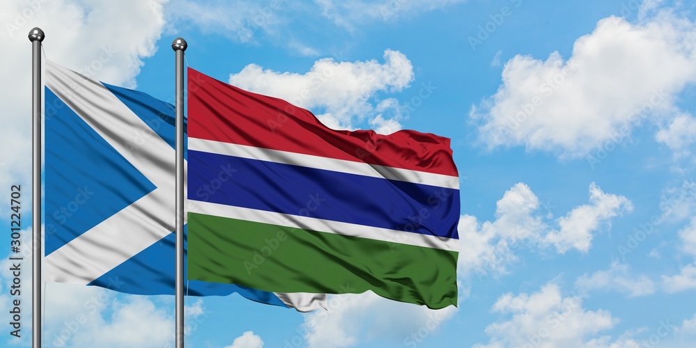 Scotland and Gambia flag waving in the wind against white cloudy blue sky together. Diplomacy concept, international relations.
