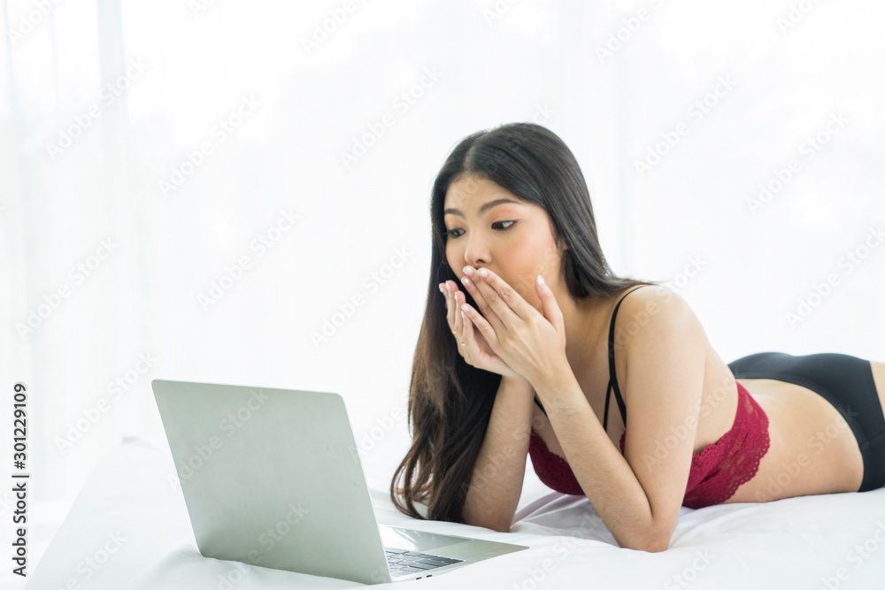 Pretty Asian woman, waking up early, excited, reading email and reading news on social networks in the morning in the bedroom. Pretty Asian woman, waking up early, excited, reading email and reading news on social networks in the morning in the bedroom.