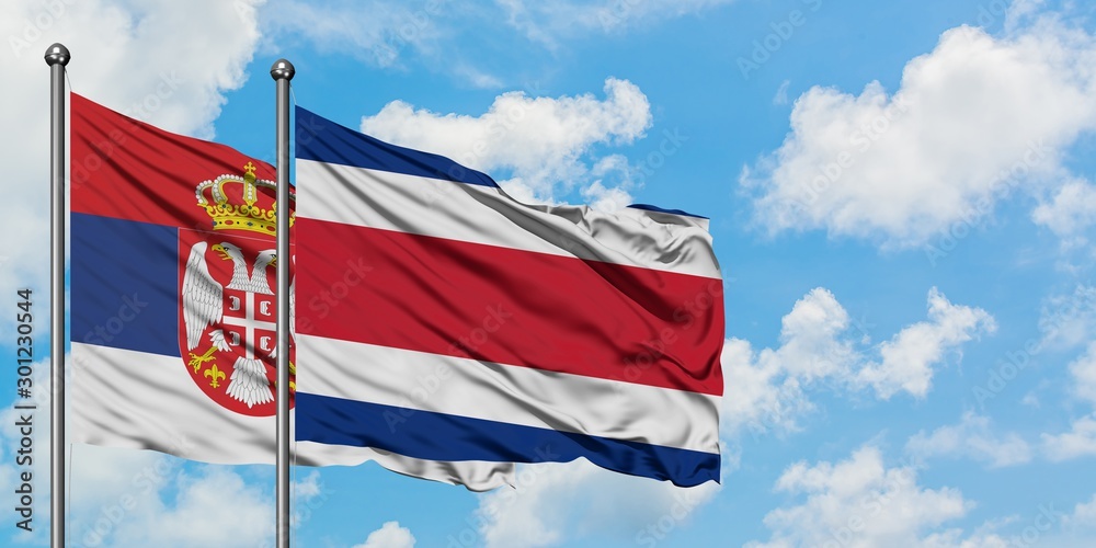 Serbia and Costa Rica flag waving in the wind against white cloudy blue sky together. Diplomacy concept, international relations.