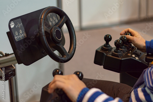 Fotografie A man controls   tractor simulator - an excavator. Joystick.