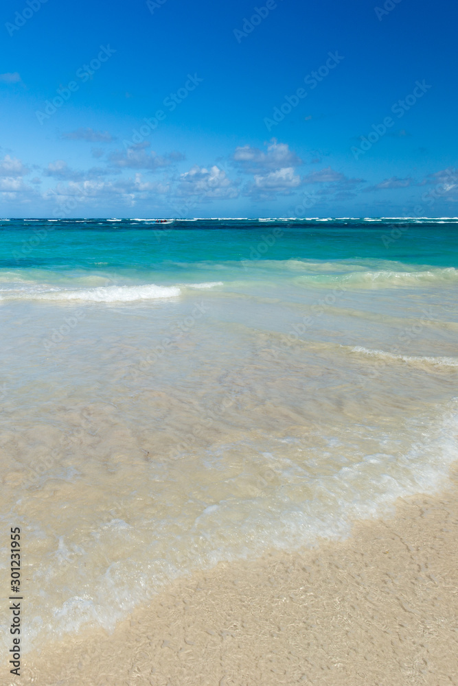 Sea wave on the sand of a tropical beach in a wild turquoise bay