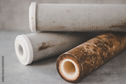 Fotografie Old used cartridges for a water filter on a gray background.