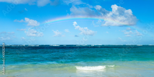 Rainbow and sunrise on the beach of a tropical bay