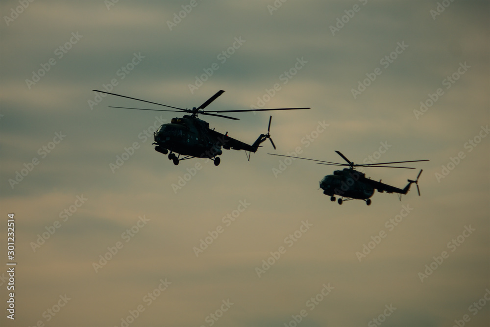 Fototapeta premium Helicopter in flight at sunset above war field