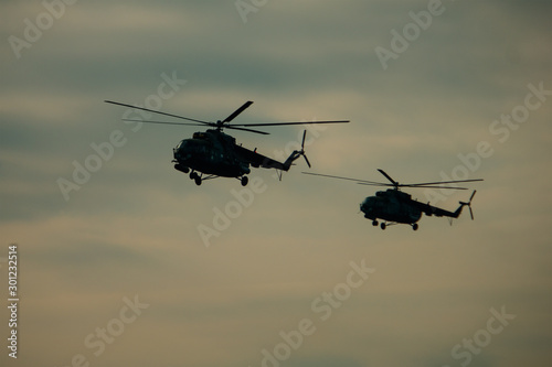 Helicopter in flight at sunset above war field