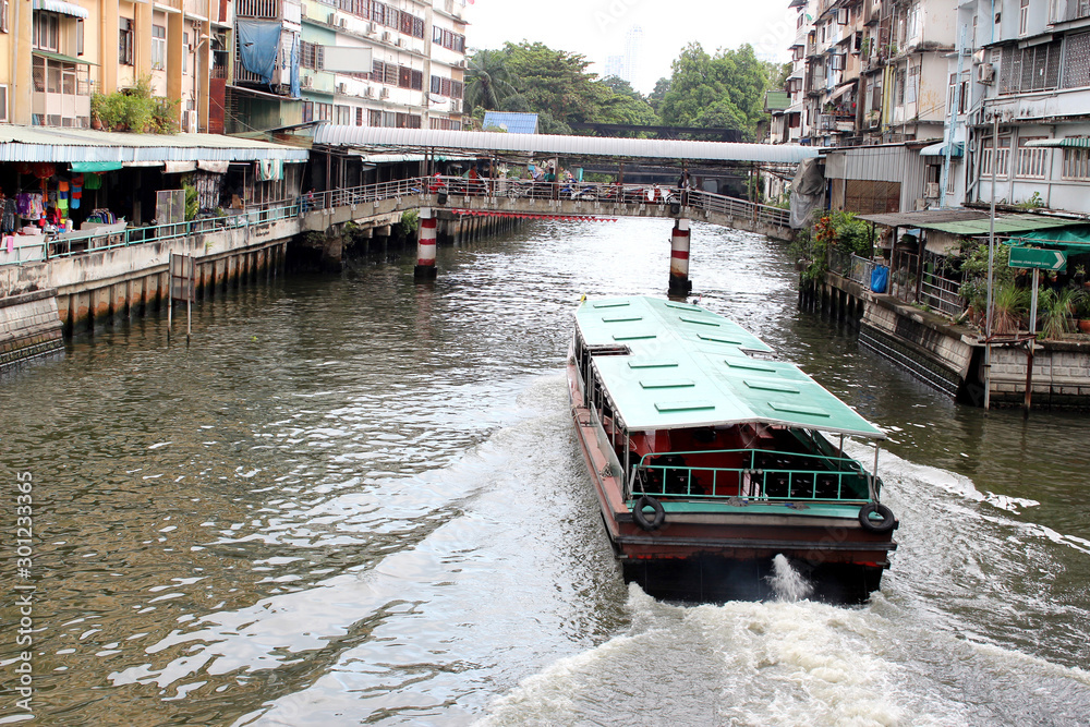 Naklejka premium Passenger boat is passing under the bridge over the canal