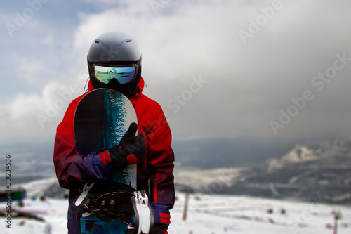 snowboarder in the foggy mountains looks directly at the camera and holds his snowboard