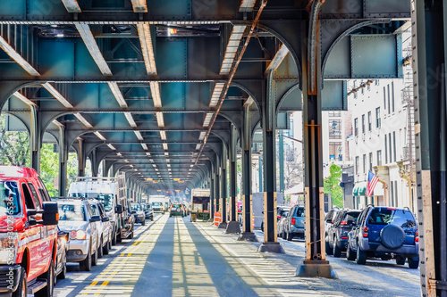 Bottom view of Elevated train track nyc. Traffic waiting in road in a sunny day. Travel and traffic concepts. Bronx, NYC, USA