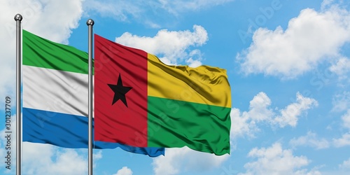 Photos Sierra Leone and Guinea Bissau flag waving in the wind against white cloudy blue sky together