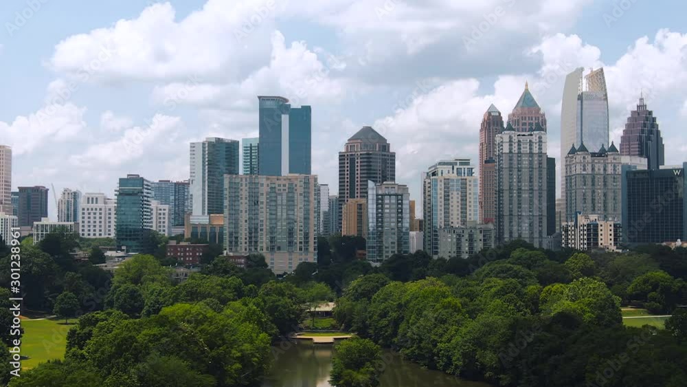 Tight aerial of downtown Atlanta buildings with green trees blue sky and clouds Tight aerial of downtown Atlanta buildings with green trees blue sky and clouds