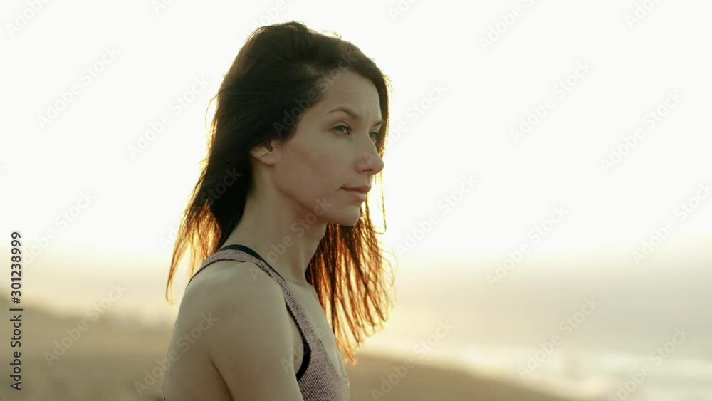Close-up shot of face of beautiful woman breathing gently, sitting at beach, practicing spiritual yoga by the Mediterranean sea at summer morning. Calella. Barcelona. Spain. Slow motion. HD Close-up shot of face of beautiful woman breathing gently, sitting at beach, practicing spiritual yoga by the Mediterranean sea at summer morning. Calella. Barcelona. Spain. Slow motion. HD