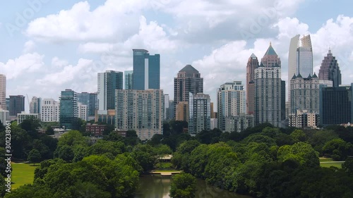 Tight aerial of downtown Atlanta buildings with green trees blue sky and clouds