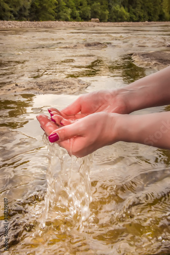 Water flows through your fingers. Hands gathered water in the river