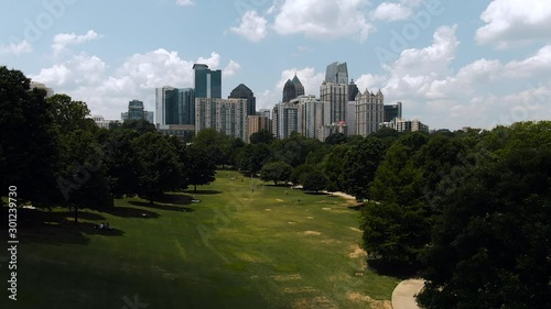 Atlanta skyline wide cinematic aerial flying low through park rising above trees