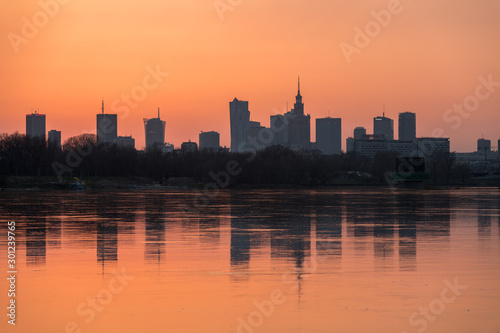 Panorama wieżowców w Warszawie podczas kolorowego zachodu słońca, odbicie w Wiśle, Polska #301239765