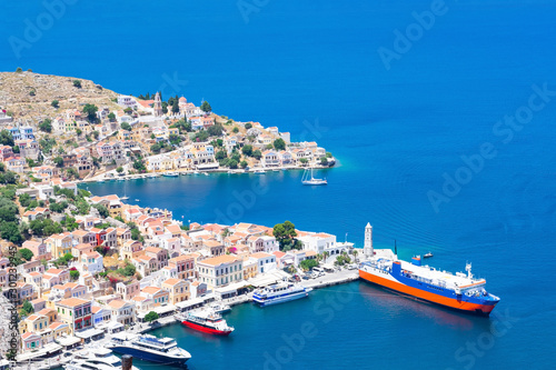 Picturesque detailed bird's eye view on tiny colorful houses on rocks and group of boats near the Mediterranian sea on Greek island in sunny summer day, vacation on exotic islands