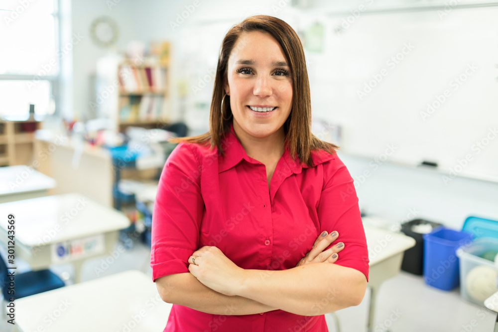 Pretty teacher smiling at camera at back of classroom at the elementary school Pretty teacher smiling at camera at back of classroom at the elementary school