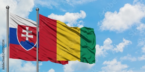 Photography Slovakia and Guinea flag waving in the wind against white cloudy blue sky together