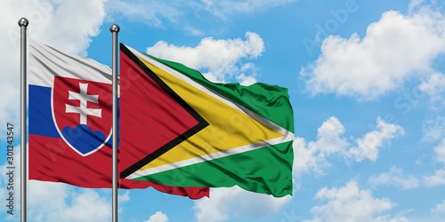 Photography Slovakia and Guyana flag waving in the wind against white cloudy blue sky together