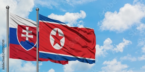 Photography Slovakia and North Korea flag waving in the wind against white cloudy blue sky together