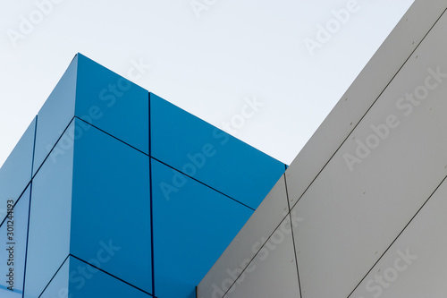 Geometric colored building facade elements with planes, lines and corners with light flare and reflections for an abstract background and texture of white, blue, gray colors. Place for text