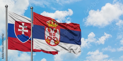 Canvas Print Slovakia and Serbia flag waving in the wind against white cloudy blue sky together