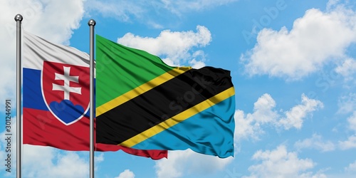 Photography Slovakia and Tanzania flag waving in the wind against white cloudy blue sky together