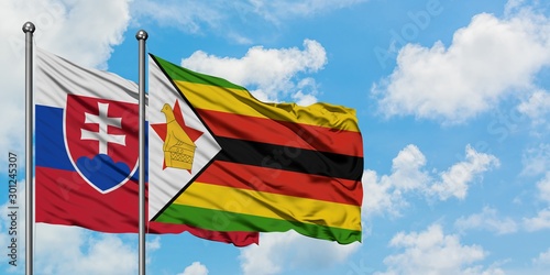 Photography Slovakia and Zimbabwe flag waving in the wind against white cloudy blue sky together
