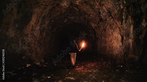 Speleologist walking inside a cave holding a flame torch. 4k