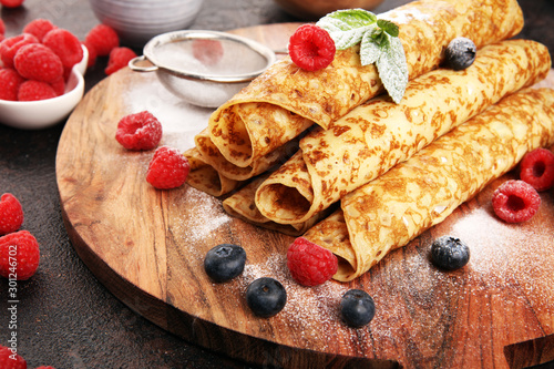 Delicious Tasty Homemade crepes or pancakes with raspberries and mint on rustic background