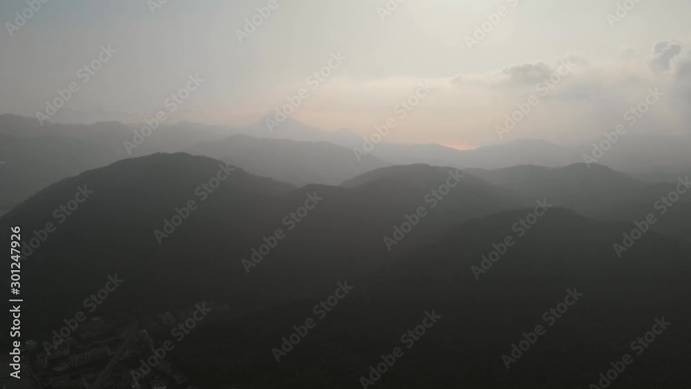 AERIAL: Flying over steep hill towards the mountains. The camera flies towards the misty mountains. Fog in the mountains