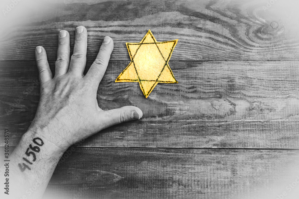 Male hand and star of David on a wooden board background. Holocaust Remembrance Day