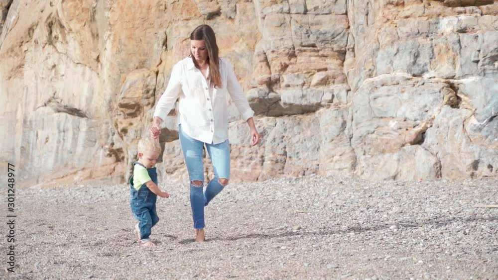 Mom walking with her son on beach. Slow motion. Mom walking with her son on beach. Slow motion.