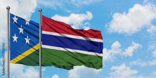 Solomon Islands and Gambia flag waving in the wind against white cloudy blue sky together. Diplomacy concept, international relations.