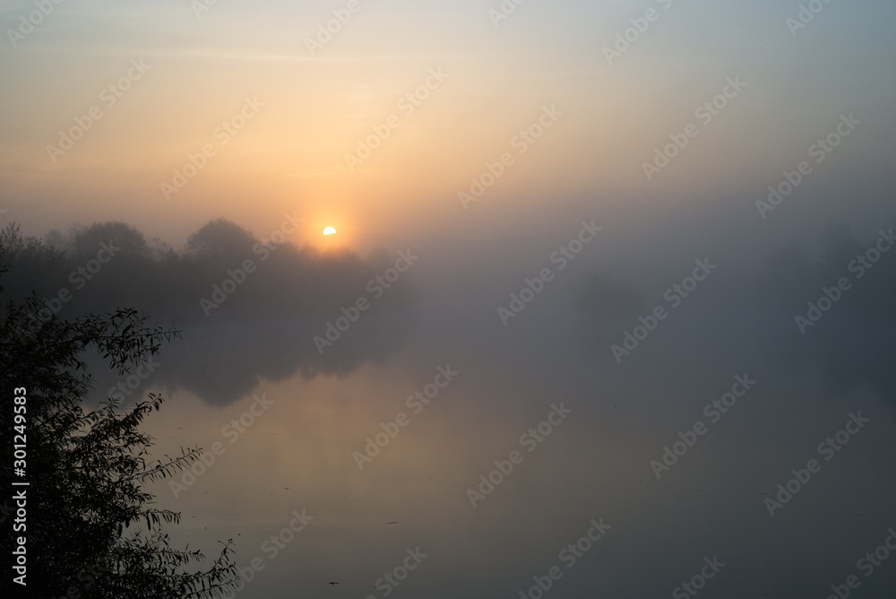 Moody atmosphere as the sun rises above a misty river