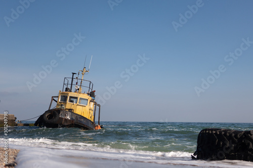 Foto Sea tug sunken during a storm at the pier on a sunny autumn day.