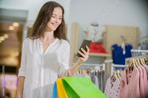girl in the store with shopping looks at the phone