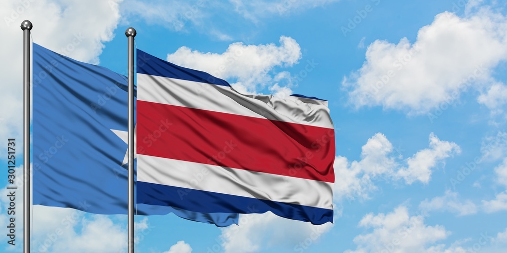 Somalia and Costa Rica flag waving in the wind against white cloudy blue sky together. Diplomacy concept, international relations.