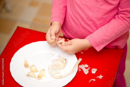 Child peeling garlic on a plate