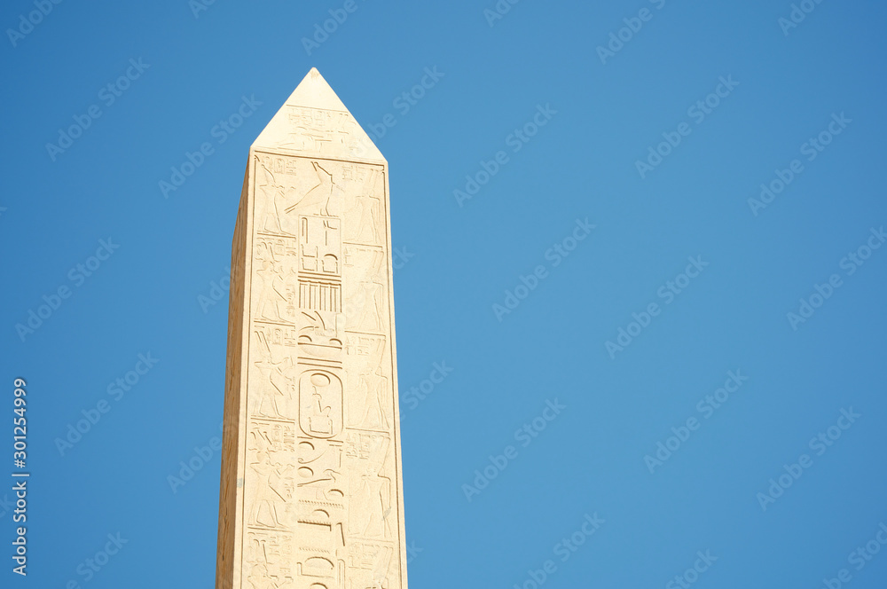 Bright blue sky view of finely detailed hieroglyphs line the well preserved obelisk at Karnak in Luxor, Egypt
